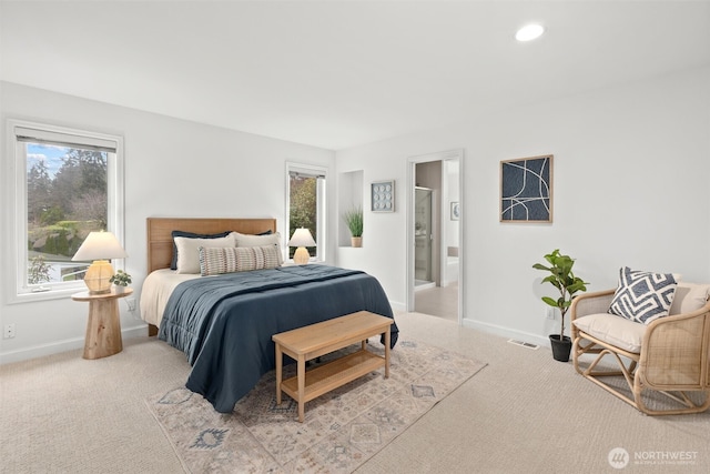carpeted bedroom featuring baseboards, ensuite bathroom, visible vents, and multiple windows