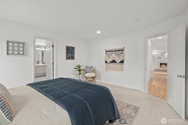 bedroom featuring a lit fireplace, carpet floors, baseboards, connected bathroom, and recessed lighting