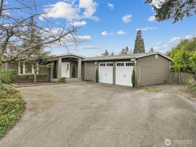 view of front facade featuring an attached garage, aphalt driveway, and fence