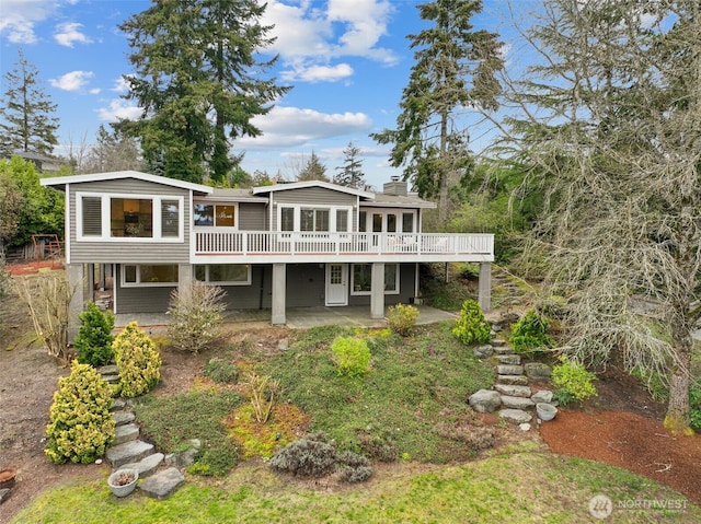 rear view of house with a patio, a wooden deck, and a chimney