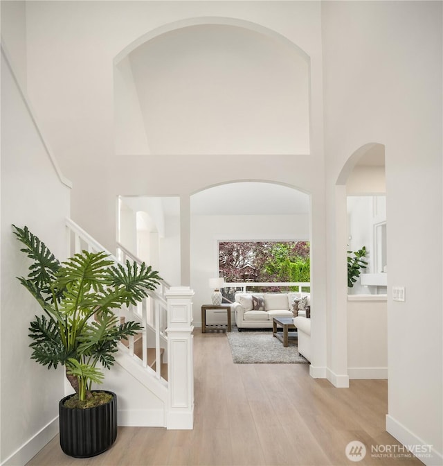 24858 NE 1st Pl, Sammamish, WA 98074 - hallway with a high ceiling, light wood finished floors, stairs, baseboards, and arched walkways