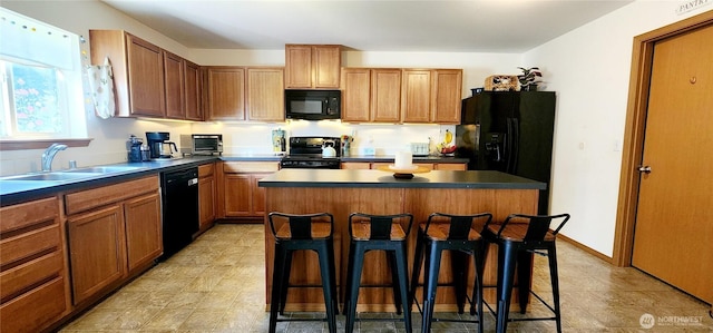 kitchen featuring a kitchen breakfast bar, dark countertops, a sink, and black appliances