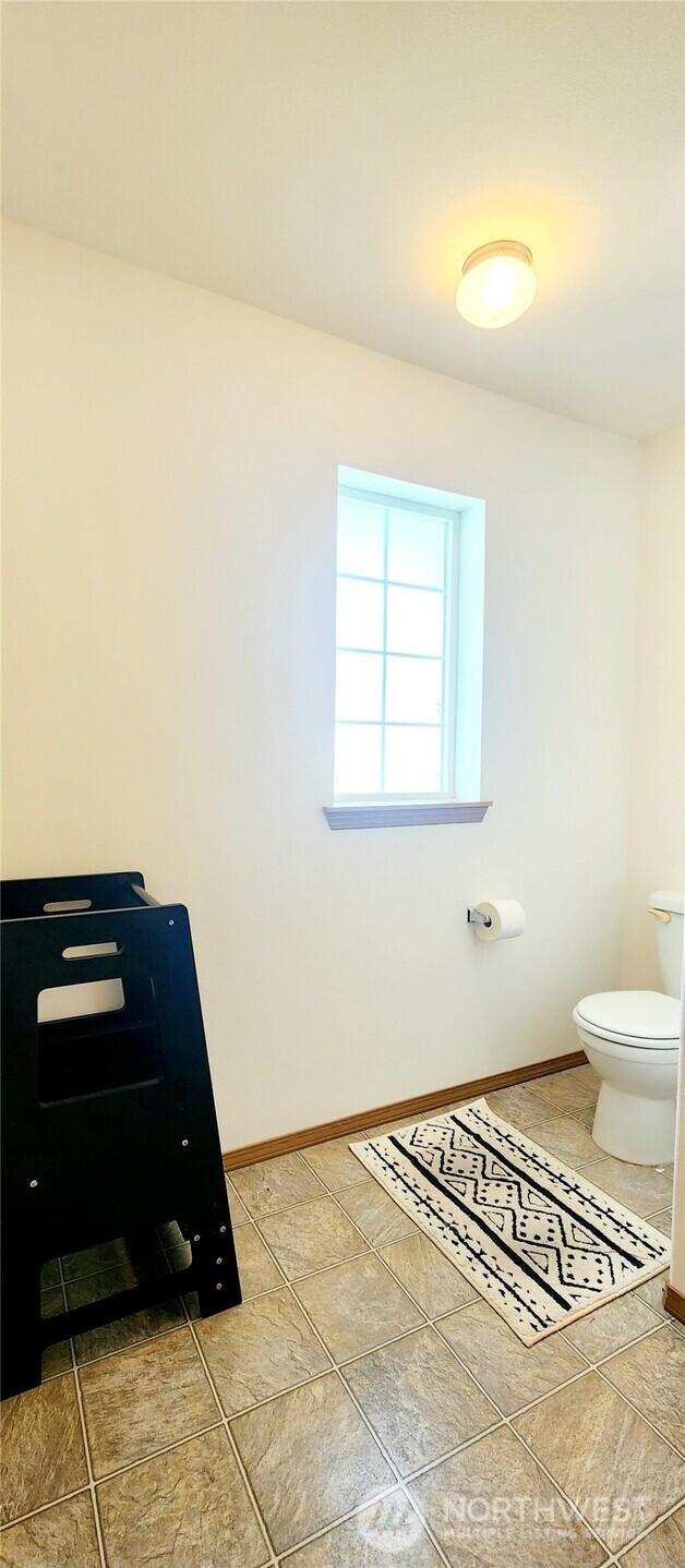 bathroom with toilet, baseboards, and tile patterned floors