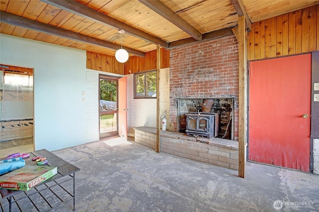 unfurnished living room with a wood stove, beam ceiling, and wood ceiling