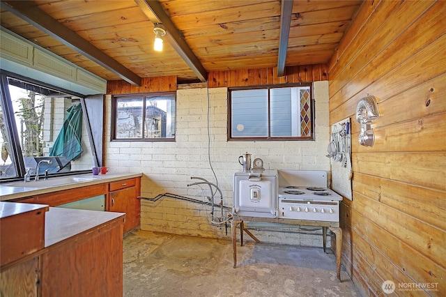interior space with a sink, wooden ceiling, wooden walls, beamed ceiling, and concrete floors