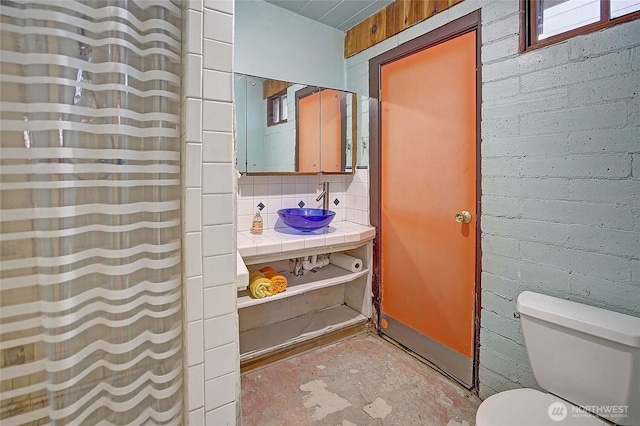 full bath featuring toilet, a sink, unfinished concrete flooring, and curtained shower