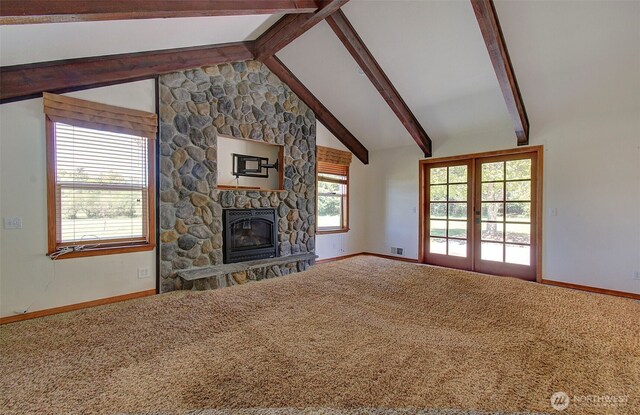 unfurnished living room with carpet, baseboards, a stone fireplace, and vaulted ceiling with beams