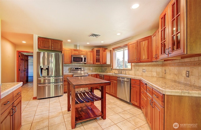 kitchen with visible vents, a sink, decorative backsplash, tile counters, and stainless steel appliances