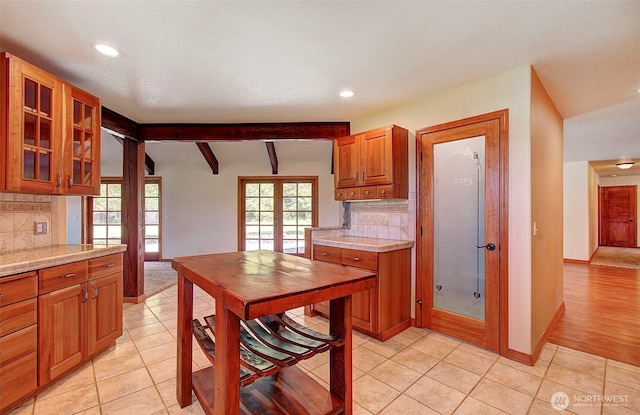 kitchen with brown cabinetry, decorative backsplash, glass insert cabinets, and recessed lighting