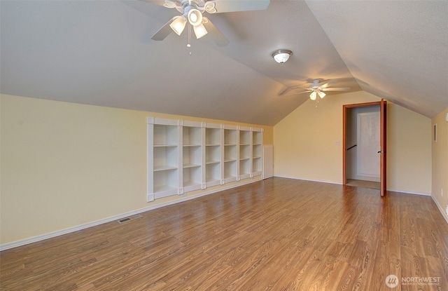 additional living space with lofted ceiling, wood finished floors, visible vents, ceiling fan, and baseboards