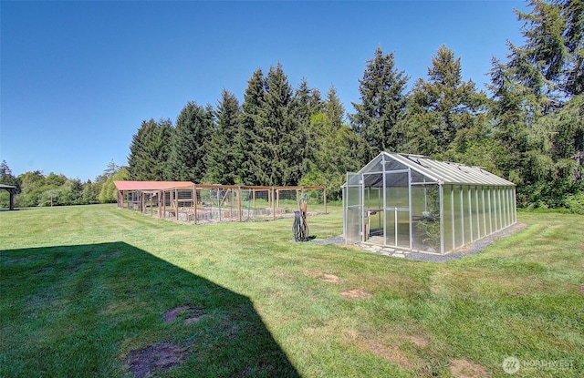 view of yard featuring a greenhouse and an outbuilding