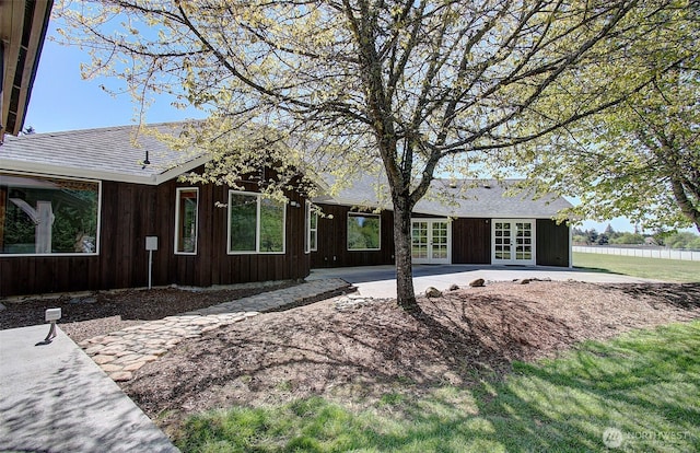 exterior space featuring a patio area, a shingled roof, and french doors