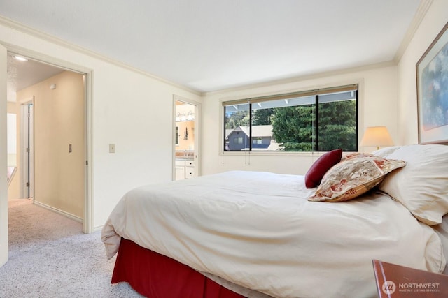 carpeted bedroom with ornamental molding, ensuite bath, and a sink
