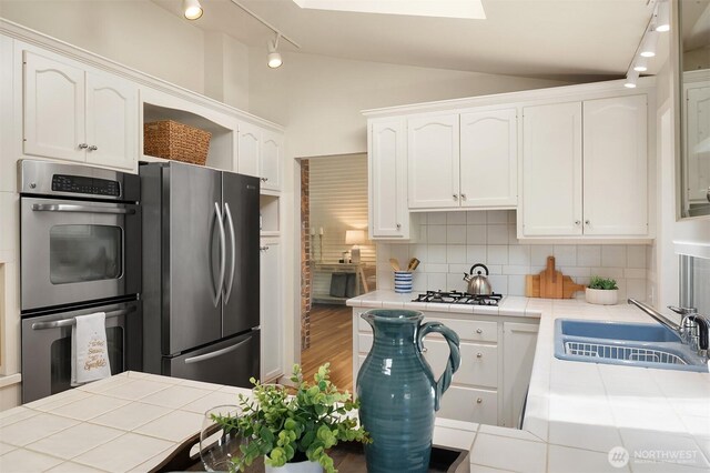 12802 NE 26th Pl, Bellevue, WA 98005 - kitchen featuring tile countertops, stainless steel appliances, a sink, white cabinetry, and decorative backsplash
