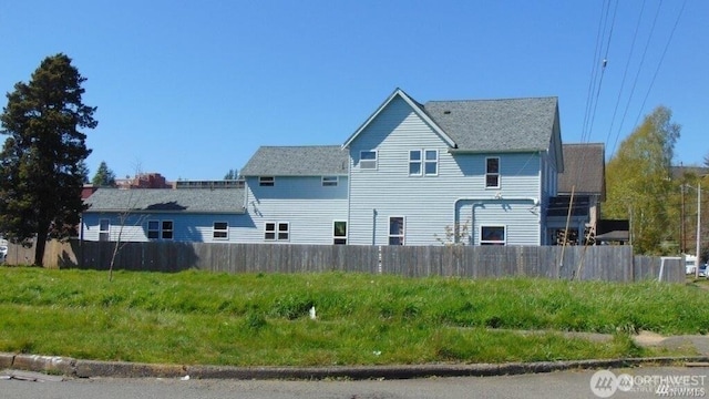 view of home's exterior with a shingled roof and fence