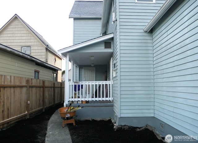 view of side of home featuring a porch and fence