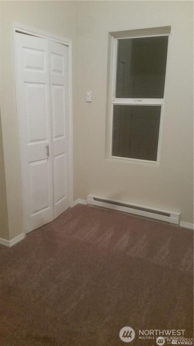 carpeted empty room with baseboards and a baseboard heating unit