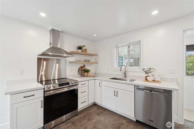 kitchen with wall chimney range hood, stainless steel appliances, a sink, open shelves, and white cabinets