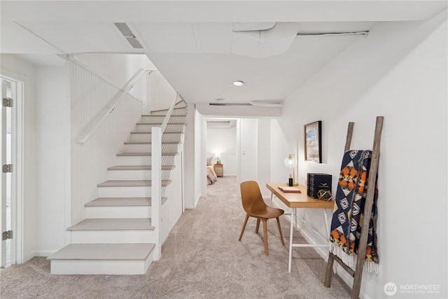 carpeted office space featuring a wall mounted air conditioner and baseboards