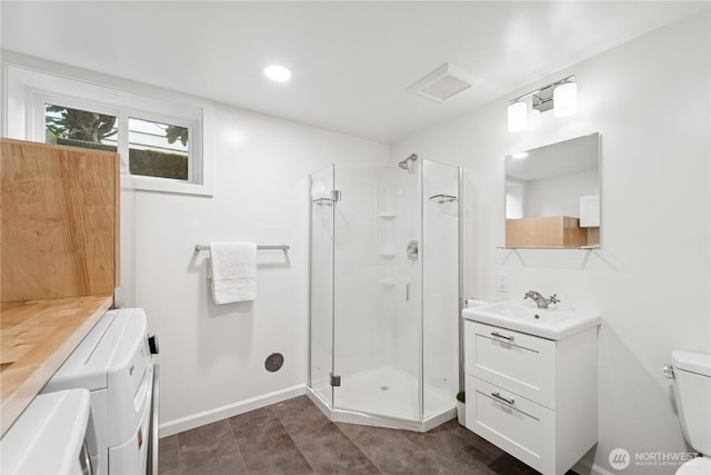 bathroom with washer and clothes dryer, a stall shower, toilet, vanity, and recessed lighting