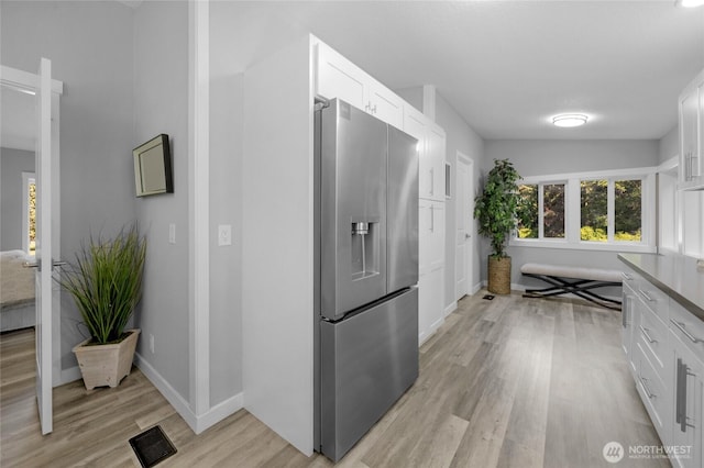 hall featuring light wood finished floors, baseboards, and visible vents