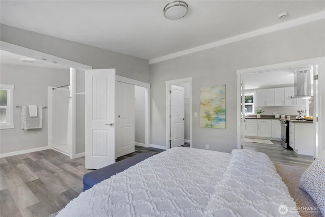 bedroom with connected bathroom, baseboards, and wood finished floors