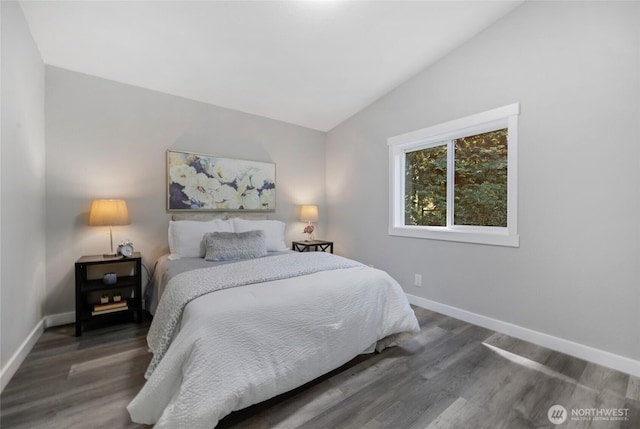 bedroom featuring baseboards, wood finished floors, and lofted ceiling