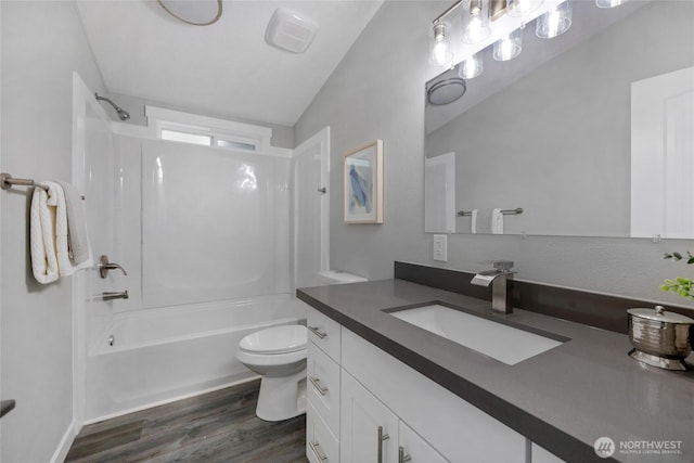 bathroom with toilet, wood finished floors, washtub / shower combination, lofted ceiling, and vanity