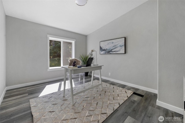 office space featuring lofted ceiling, baseboards, and wood finished floors
