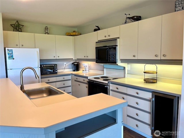 kitchen with a sink, freestanding refrigerator, electric range oven, wine cooler, and black microwave