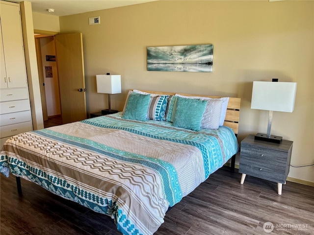 bedroom with baseboards, visible vents, and wood finished floors