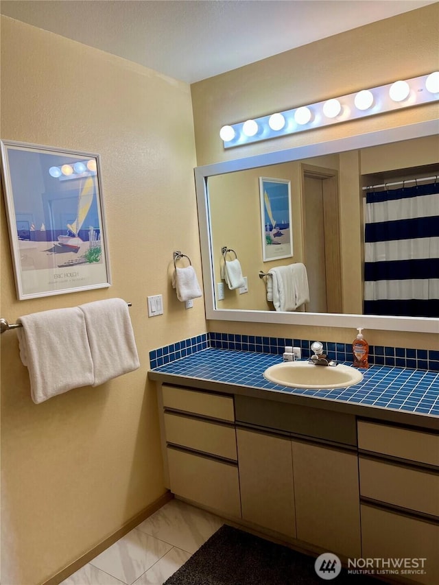 bathroom with baseboards, marble finish floor, and vanity