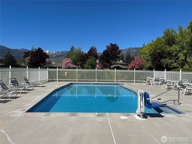 pool featuring a patio area, a mountain view, and fence