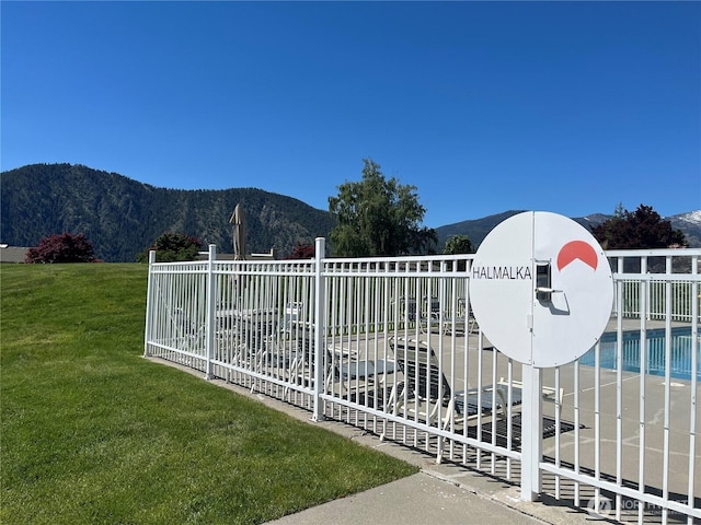 view of gate with a yard, fence, and a mountain view