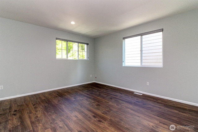 empty room featuring visible vents, baseboards, dark wood-type flooring, and recessed lighting