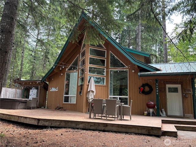 back of house with a hot tub and a deck