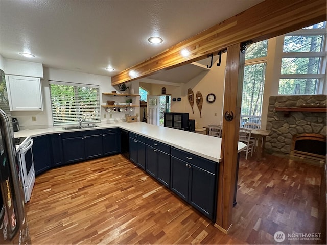 kitchen with a sink, light wood finished floors, light countertops, open shelves, and recessed lighting