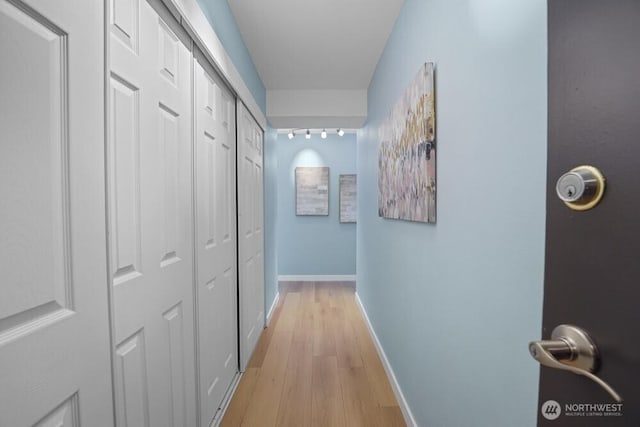 hall with light wood-style floors and baseboards