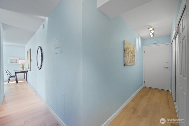corridor with light wood finished floors and baseboards