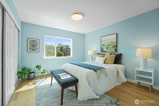 bedroom with wood finished floors, a closet, and baseboards