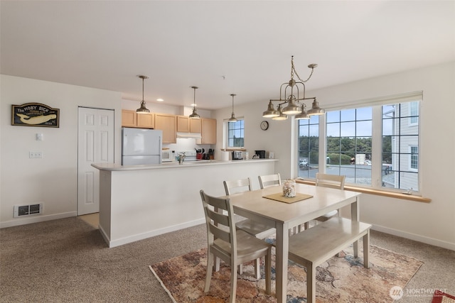 dining space featuring an inviting chandelier, baseboards, light colored carpet, and visible vents