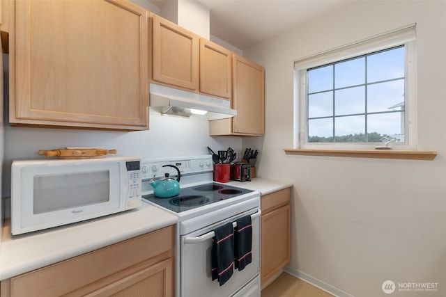 kitchen featuring light countertops, under cabinet range hood, light brown cabinets, and white appliances