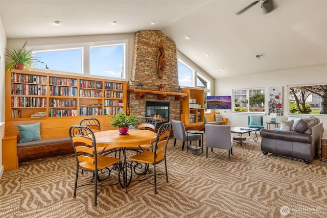 interior space featuring high vaulted ceiling, a fireplace, carpet floors, and visible vents