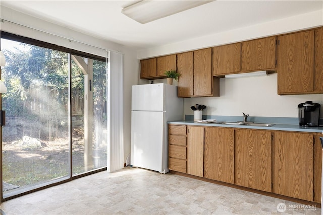 325 NE Kettle St Unit 102, Oak Harbor, WA 98277 - kitchen featuring freestanding refrigerator, brown cabinetry, a sink, and light countertops