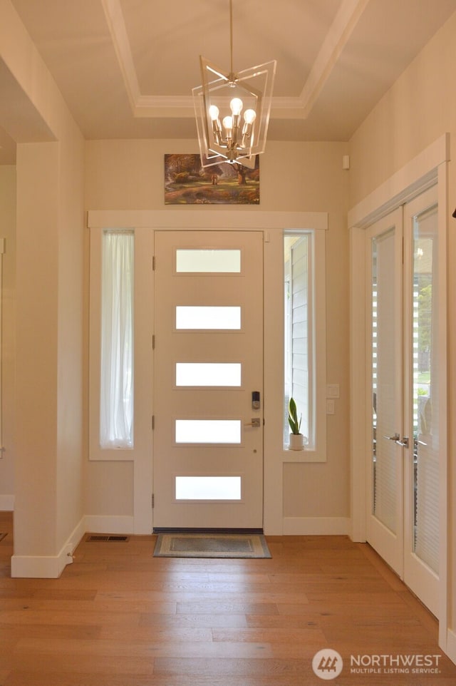 entryway featuring light wood-style flooring, a chandelier, and french doors
