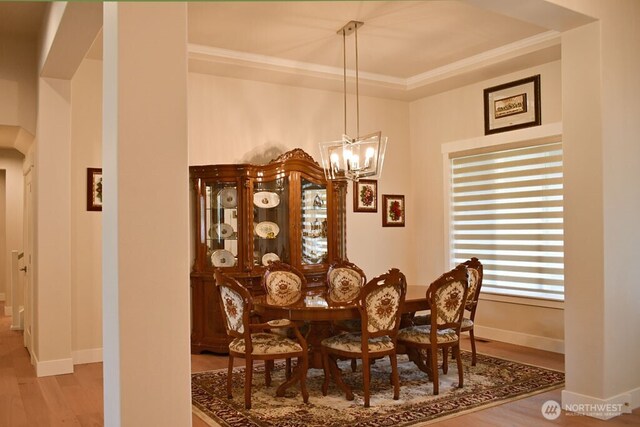 dining area with a chandelier, wood finished floors, crown molding, baseboards, and arched walkways