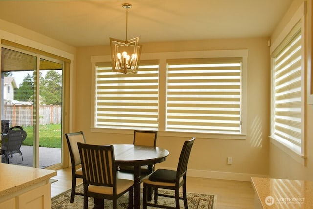 dining space featuring a chandelier, light wood finished floors, and baseboards