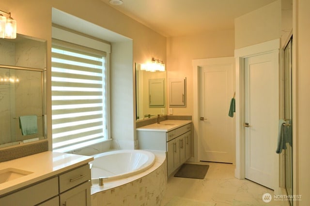 full bath featuring a marble finish shower, a garden tub, marble look tile flooring, and two vanities