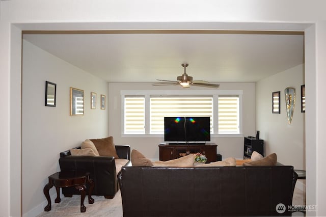 living room with healthy amount of natural light, a ceiling fan, light carpet, and baseboards