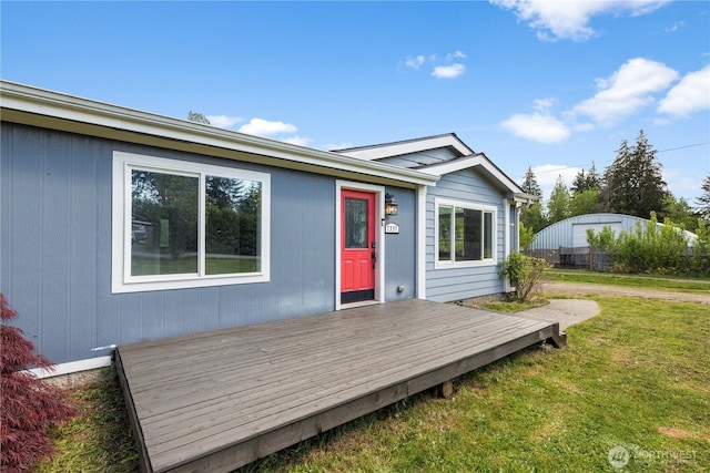 back of property featuring a deck and a lawn